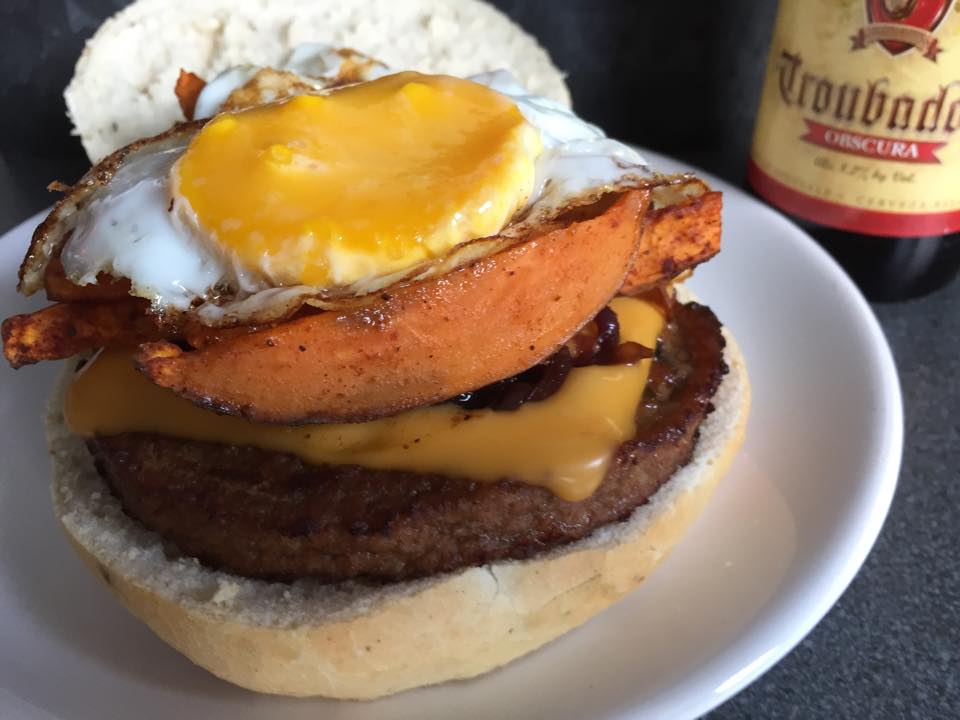 Burger vegetarian cu ou prajit, cartofi dulci si ceapa caramelizata in bere